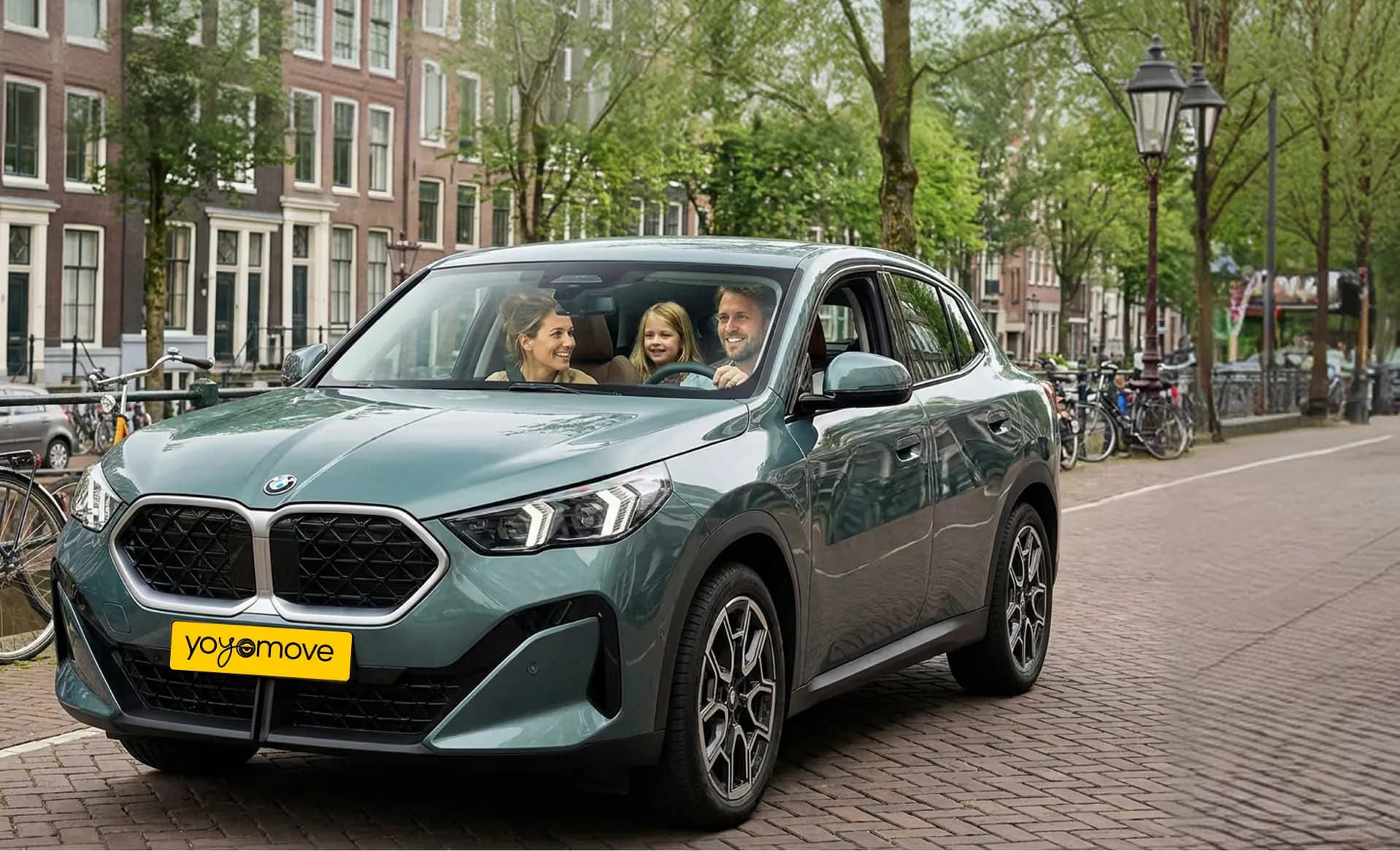 Familie in een groene BMW X2 op een Amsterdamse gracht — private lease met Yoyomove
